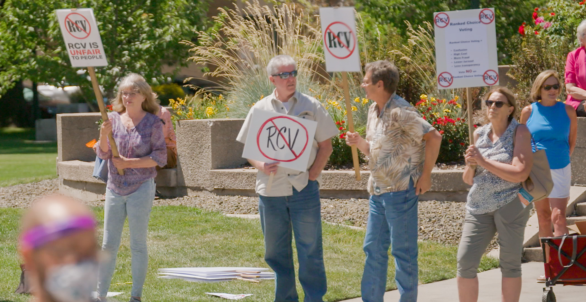 People standing outside holding signs against RCV