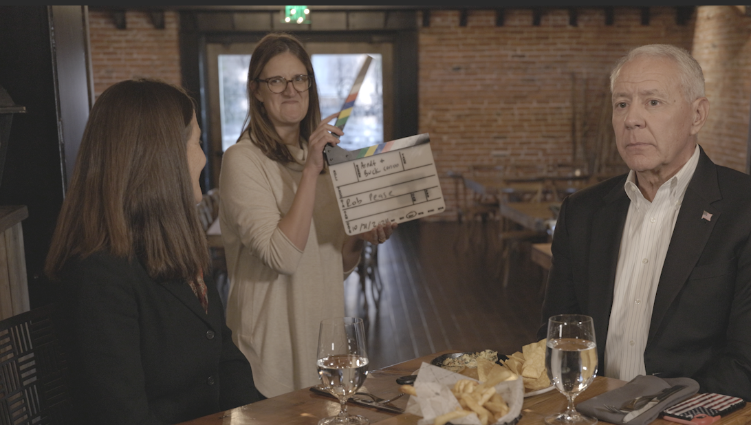 Julia Hoppock holds a clapperboard behind interviewees Jenny Arndt and Ken Buck in Colorado.