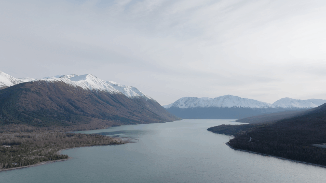Aerial view of Kenai, Alaska with a wide river flowing into distant snow-capped mountains