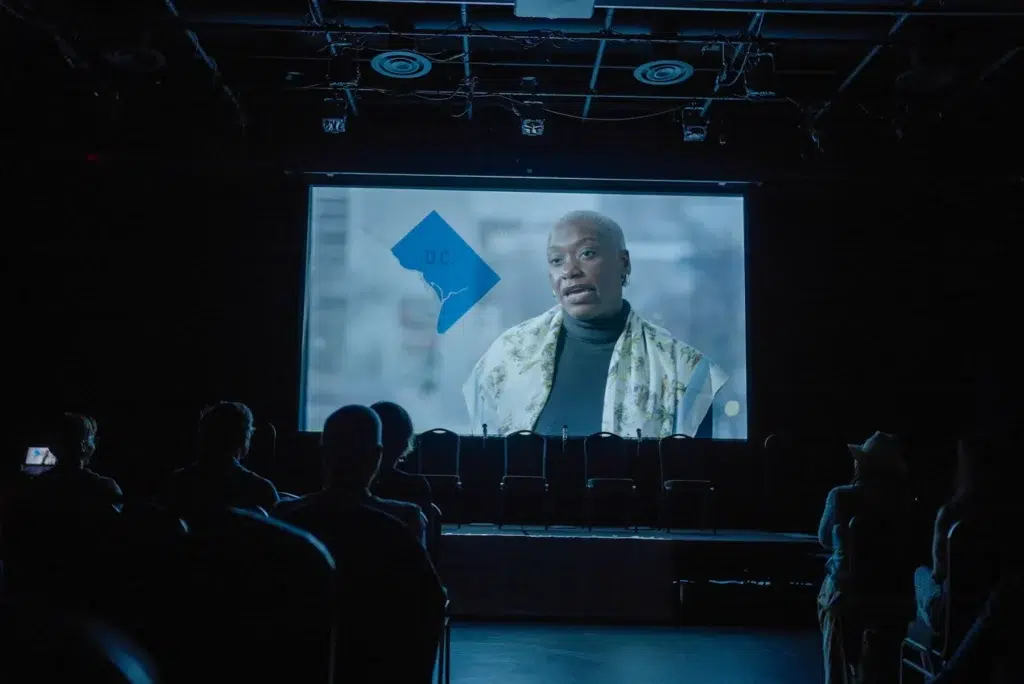 A still from People vs. Politics projected on screen, featuring Kenyatta Smith.